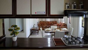 A kitchen with a stove, cabinets, and a dining area with a table and chairs.
