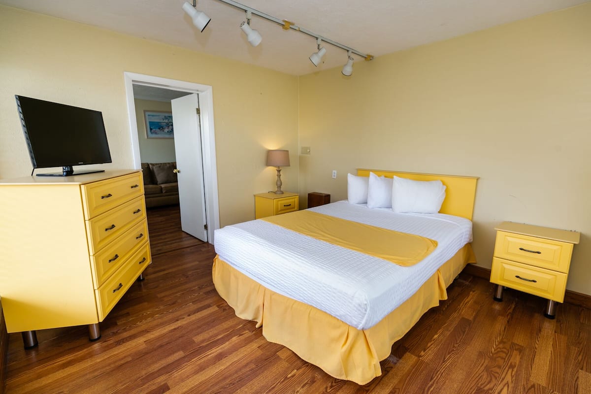 A hotel room with a bed, a TV, a dresser, and a nightstand.