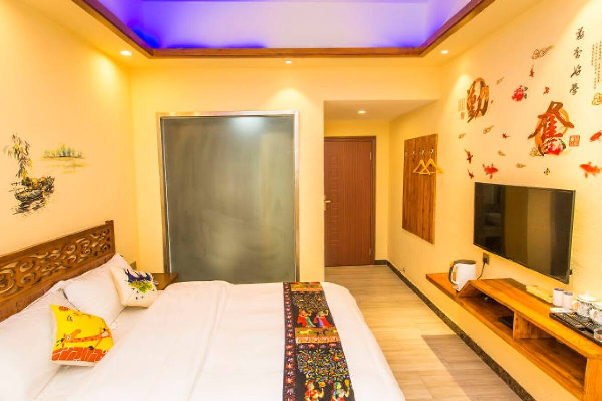Habitación de hotel con cama, televisor, banca de madera y decoración en la pared.