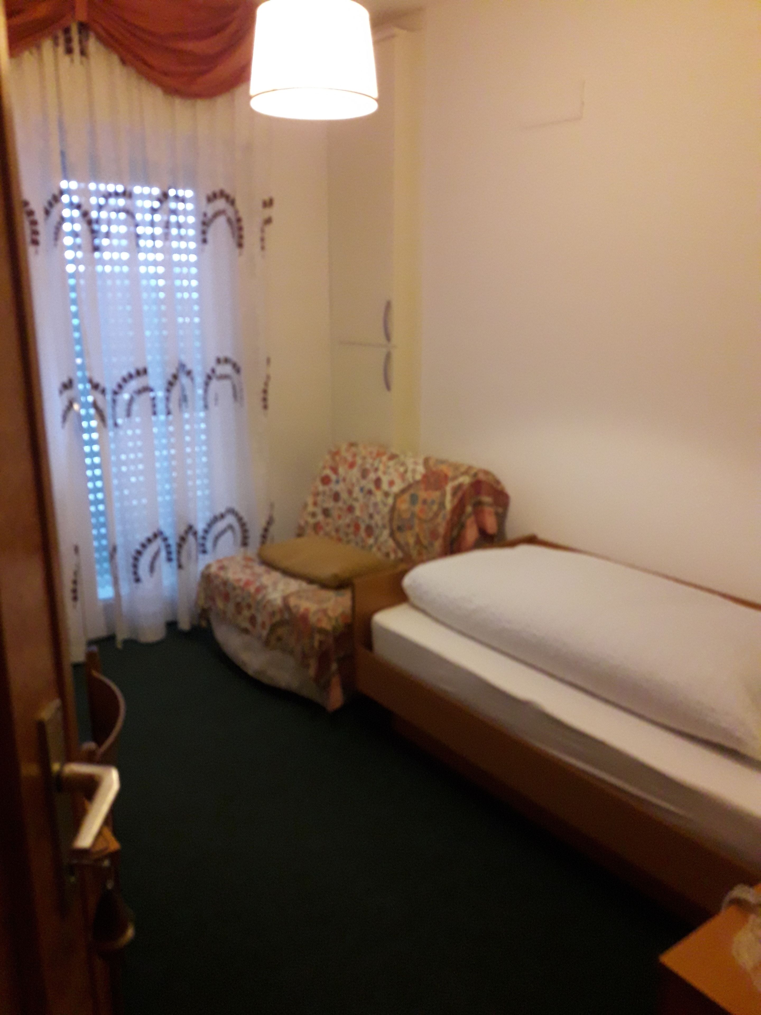 Una habitación pequeña y acogedora con una cama individual, una silla y una mesa.