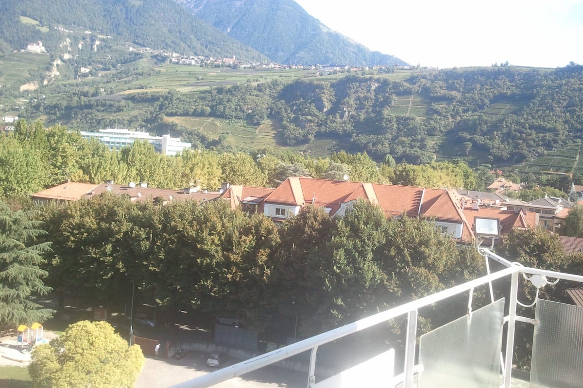 A residential area with houses, a large building, and mountains in the background.