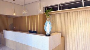 A reception desk with a marble top, wooden paneling, and a statue. - Pousada do Reinildo (Cachoeira Paulista)