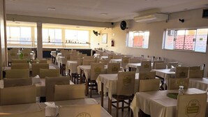 A dining area with tables and chairs, each with a 'Reinildo Empreendimentos' logo. - Pousada do Reinildo (Cachoeira Paulista)