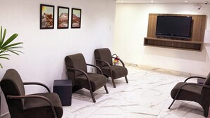 A waiting area with four chairs, a mounted TV, and three framed pictures on the wall. - Pousada do Reinildo (Cachoeira Paulista)