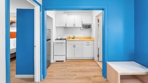 A compact kitchen with white cabinets, a microwave, and a stove. - Buttercup Suites (Wildwood Crest)