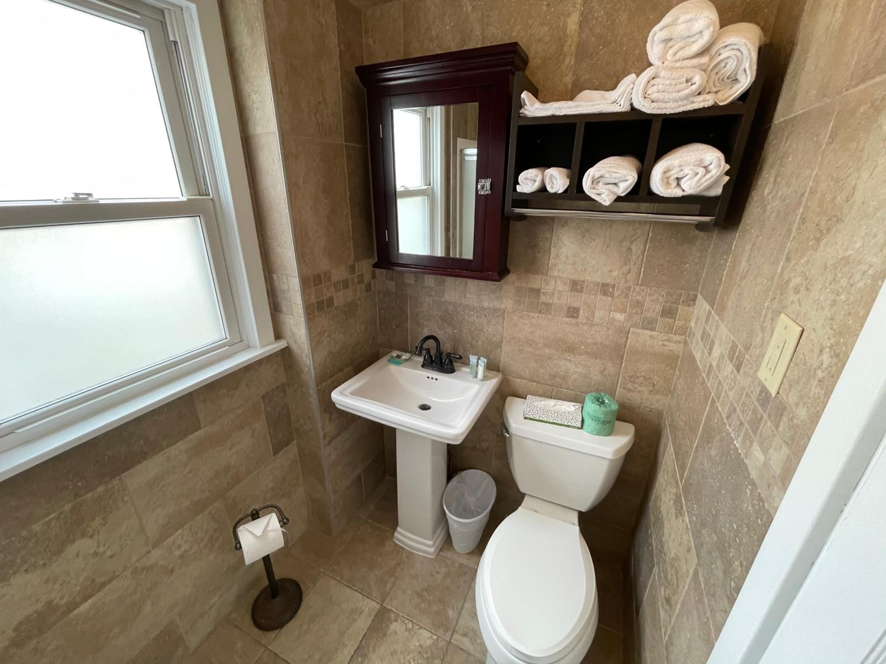 A bathroom with a sink, toilet, and a towel rack with towels.