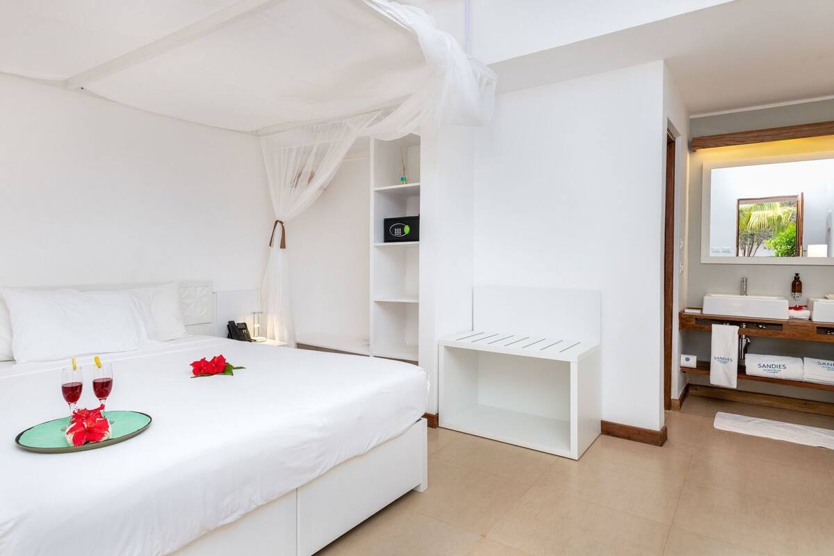 A hotel room with a bed, bedside table, and a vanity area with a mirror.