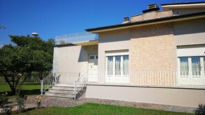 Un bâtiment à deux étages, doté d’un toit plat, d’un balcon avec des balustrades blanches et d’une façade en briques.