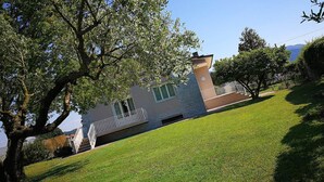 Un edificio di due piani con un balcone, circondato da prato curato e alberi.