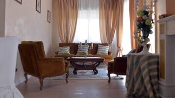 Un salon comprenant un canapé, deux fauteuils, une table basse et une cheminée.