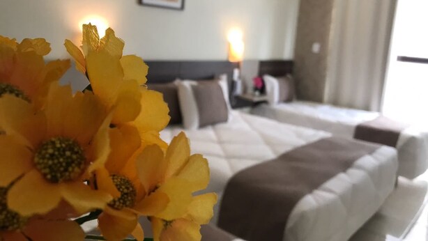 A hotel room with a bed, pillows, a bedside table, and a wall-mounted air conditioner. - Hotel do Reinildo (Cachoeira Paulista)