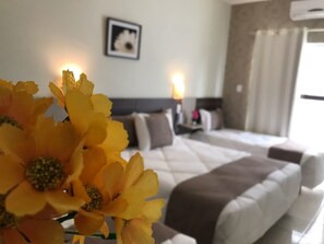 Ein Hotelzimmer mit Bett, Kissen, einem Nachttisch und einer Wand-Klimaanlage.