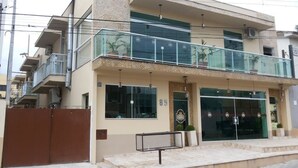 A modern building with a glass balcony, a gated entrance, and a sign indicating a business establishment. - Hotel do Reinildo (Cachoeira Paulista)