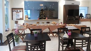 A dining area with a long table set for a meal, surrounded by chairs. - Hotel do Reinildo (Cachoeira Paulista)