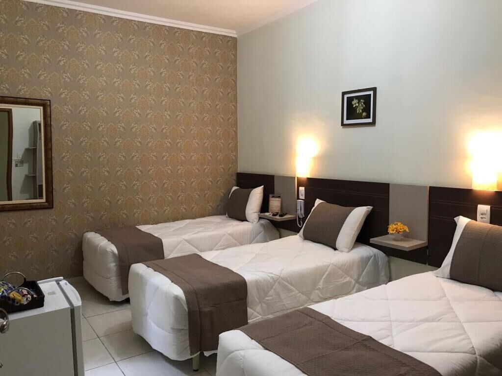 Habitación de hotel con dos camas, un escritorio pequeño y un espejo.