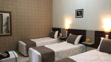 Habitación de hotel con dos camas, un escritorio pequeño y un espejo.