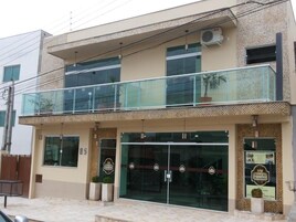 Un hotel de diseño moderno, con entrada de vidrio, balcón con plantas en macetas y un cartel anunciando el hotel.