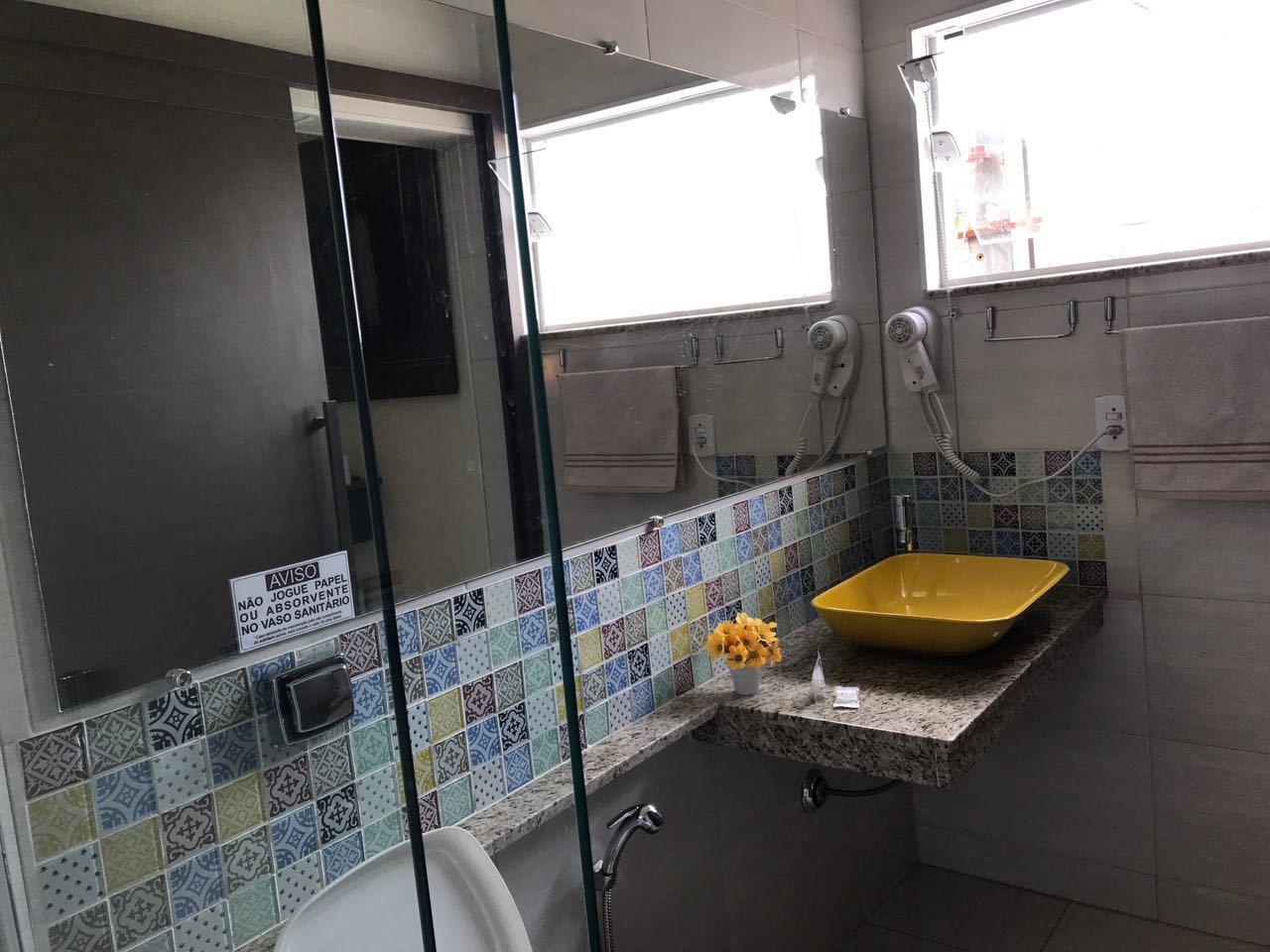 Ein Badezimmer mit einem gelben Waschbecken, einem Spiegel und einer gefliesten Rückwand.