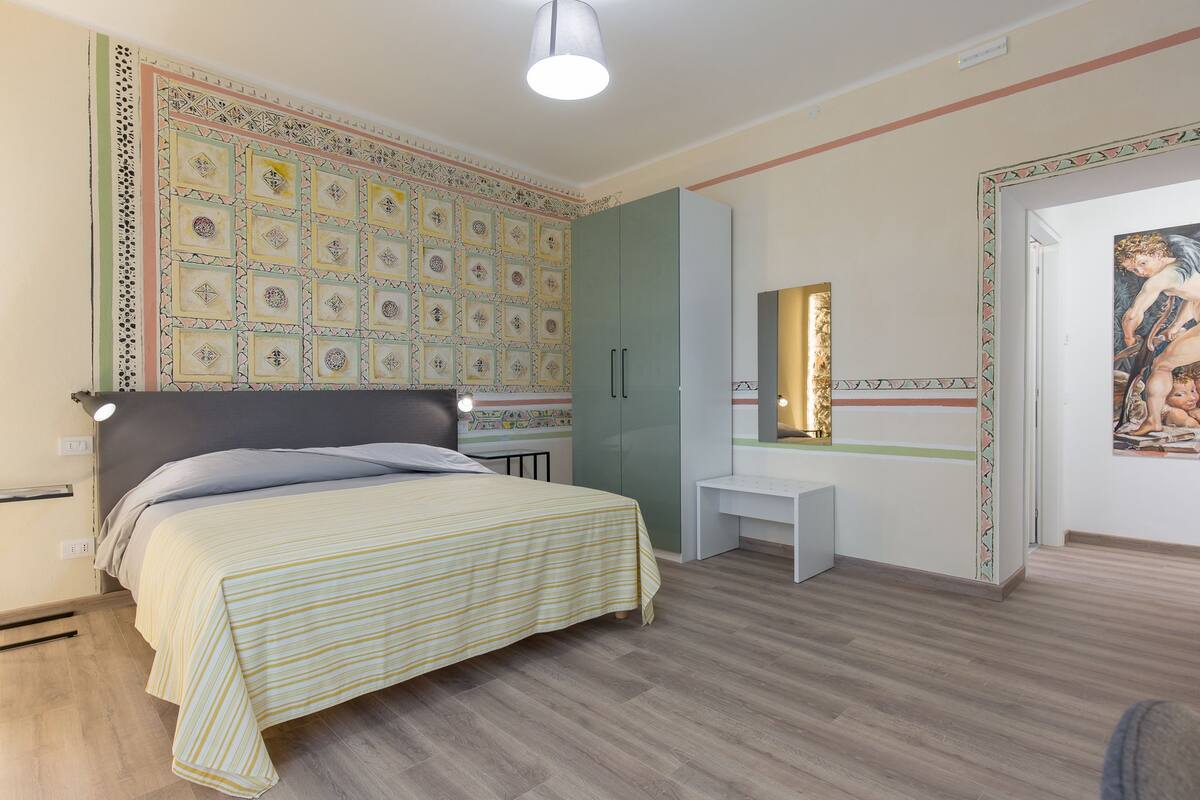 A bedroom with a bed, bedside table, and a wall with a decorative pattern.