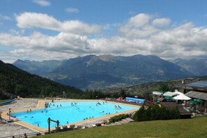 A swimming pool surrounded by mountains with clear skies. - Hotel la Portette (Les Orres)