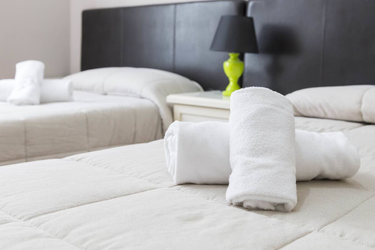 A hotel room with a neatly made bed, a bedside lamp, and a headboard.
