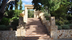 A stone staircase leading to a covered area, surrounded by greenery and trees. - Akraion (Penteli)