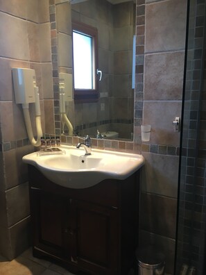 A bathroom with a large sink, vanity, mirror, and a window.