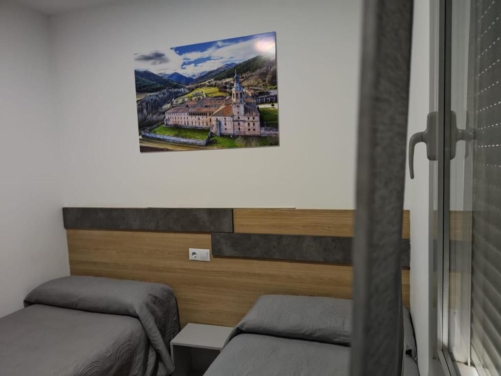 Habitación de hotel con dos camas, cabecero de madera, un cuadro colgado en la pared y una ventana con persianas.