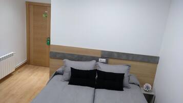 Un dormitorio con cama doble, cabecera de madera, mesita de noche y un pequeño objeto decorativo.