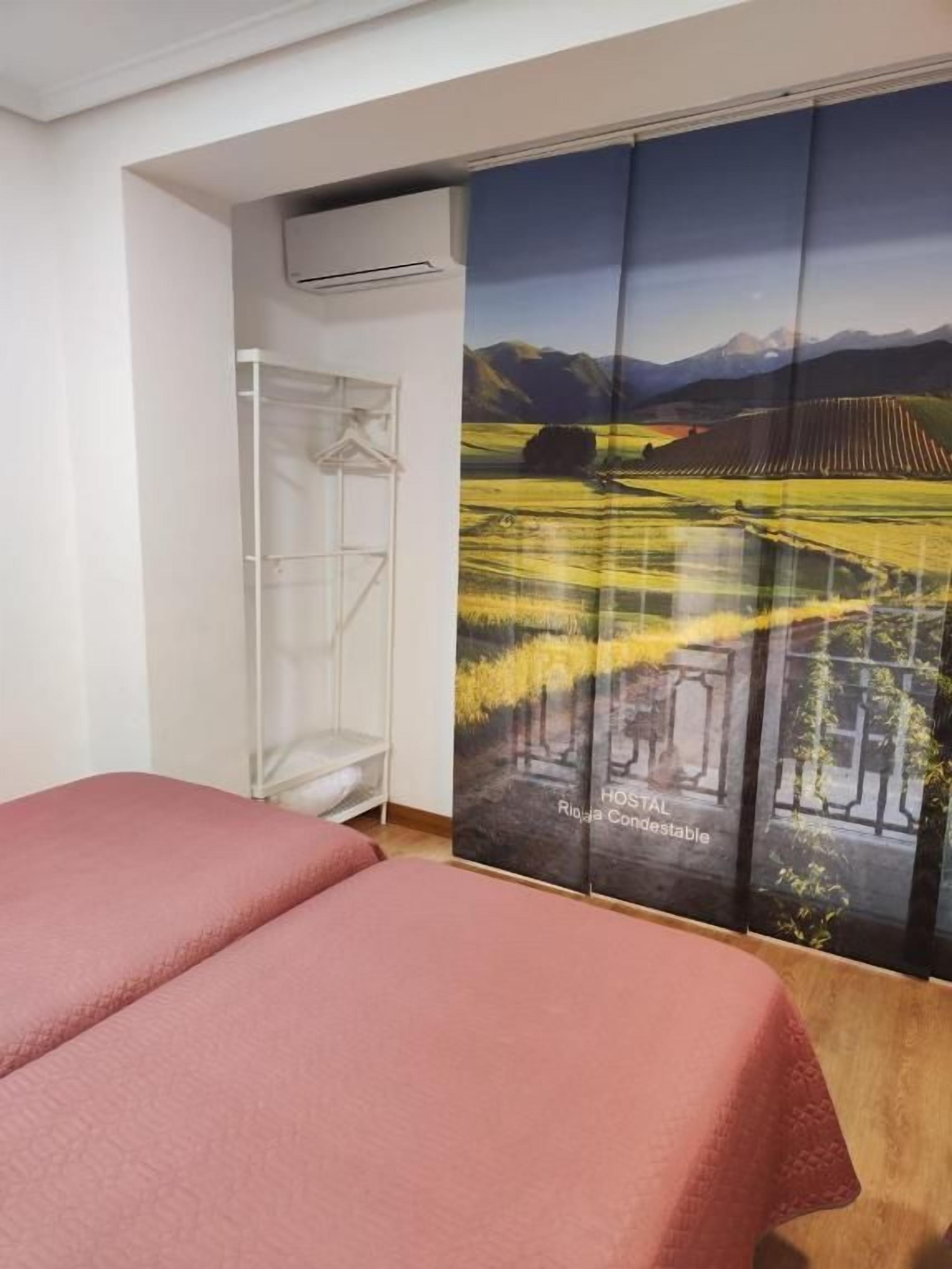 A room with a bed, a wardrobe, and a large window with a scenic view.
