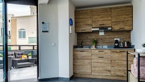 A modern kitchen with wooden cabinets, a built-in oven, and a coffee maker. There is a small potted plant on the counter. - Urban Rooms By Neu Collective (Gzira)