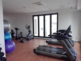 Un gimnasio con cintas de correr, bicicletas estáticas y pelotas de ejercicio.