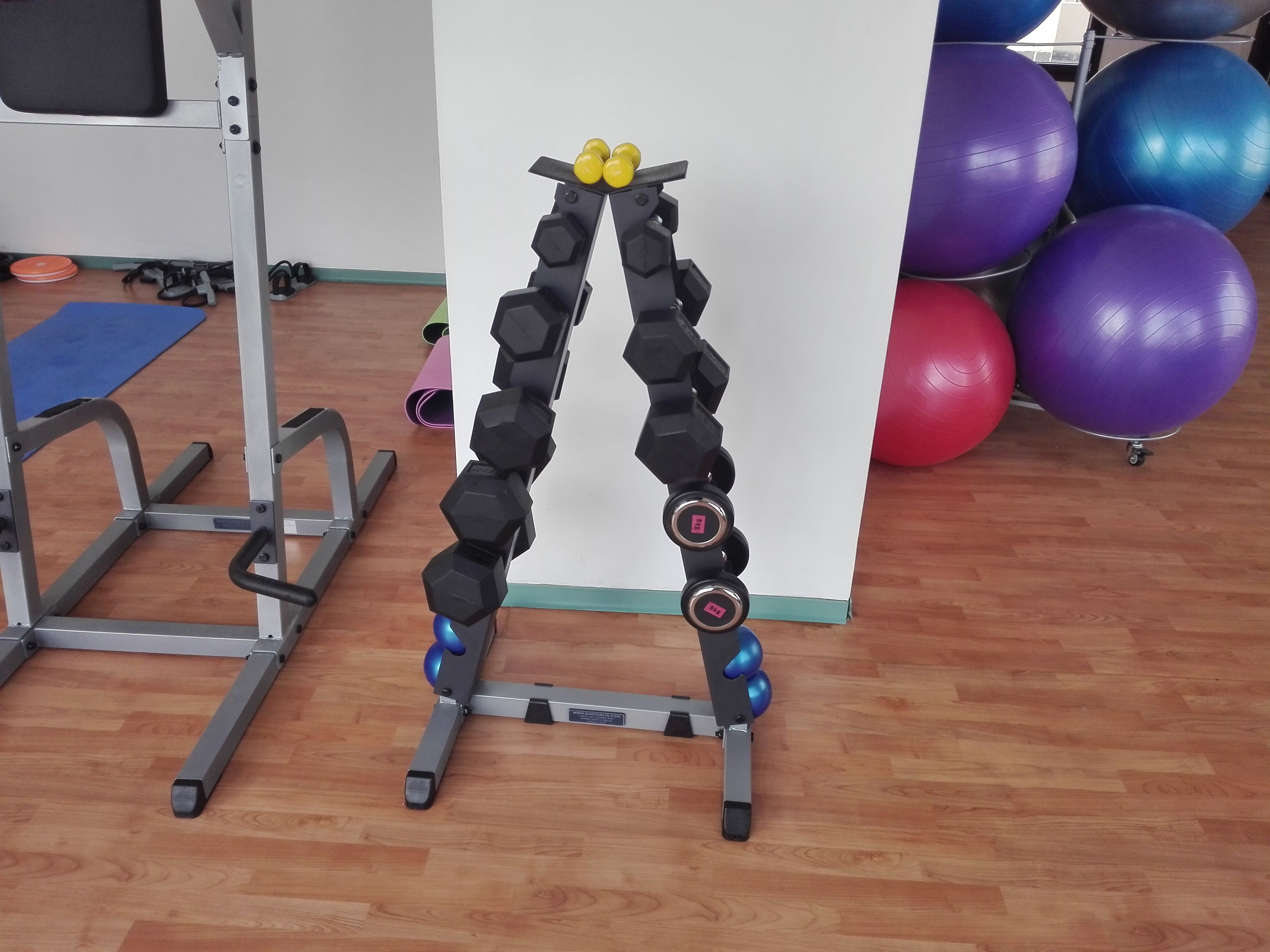 A gym with a cable machine, exercise balls, and a blue mat.