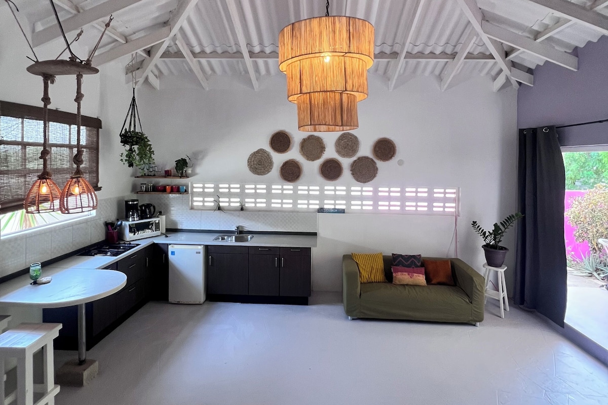 Cozinha moderna com área de refeições, luminária pendente e vista para o exterior.