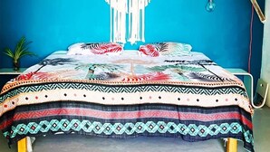 A bed with a patterned bedspread, a macrame wall hanging, and a hanging light fixture. - Tropical Breeze Apartments (Willemstad)