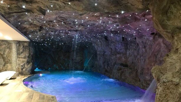 A spa area with a pool, a waterfall feature, and a ceiling with star-like lights. - National Park Hotel & Spa (Cotronei)