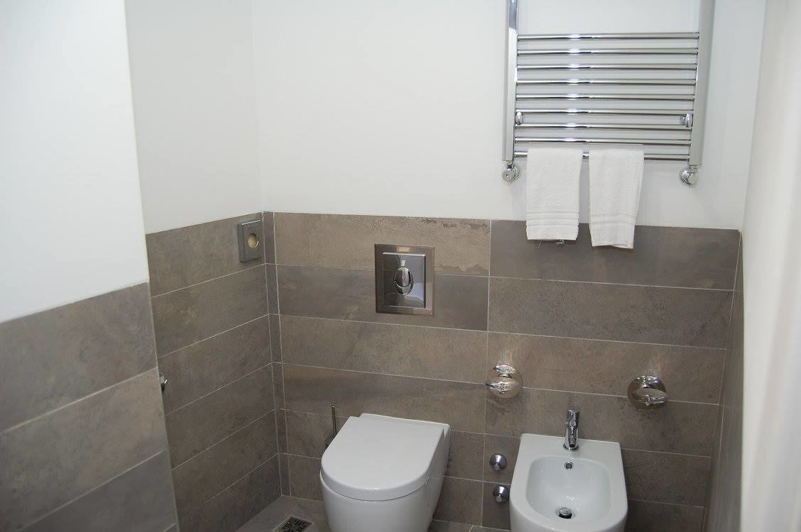 Une petite salle de bain moderne équipée de toilettes, d’un bidet et d’un porte-serviettes.