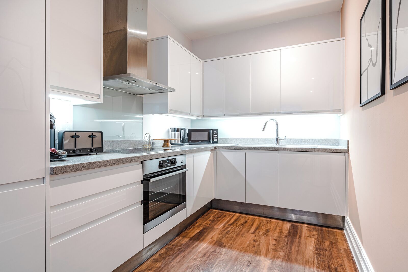 Una cocina moderna con armarios blancos, horno empotrado, microondas y tostadora.