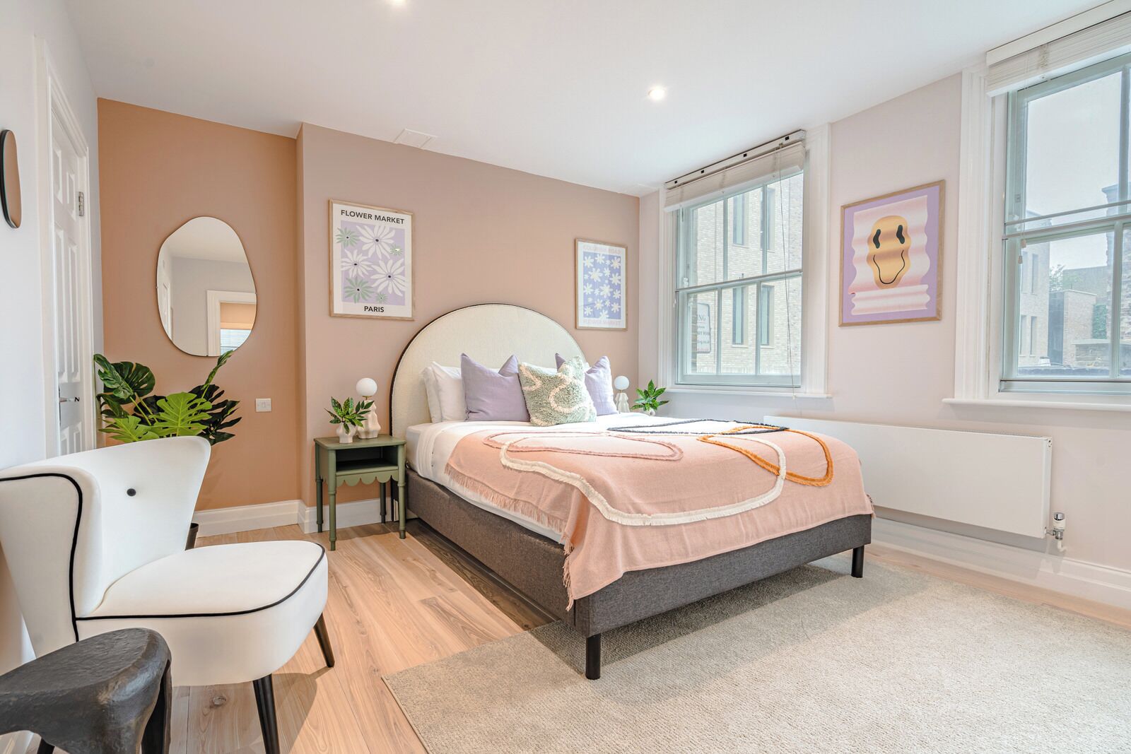 A bedroom with a bed, bedside table, chair, and a large window.