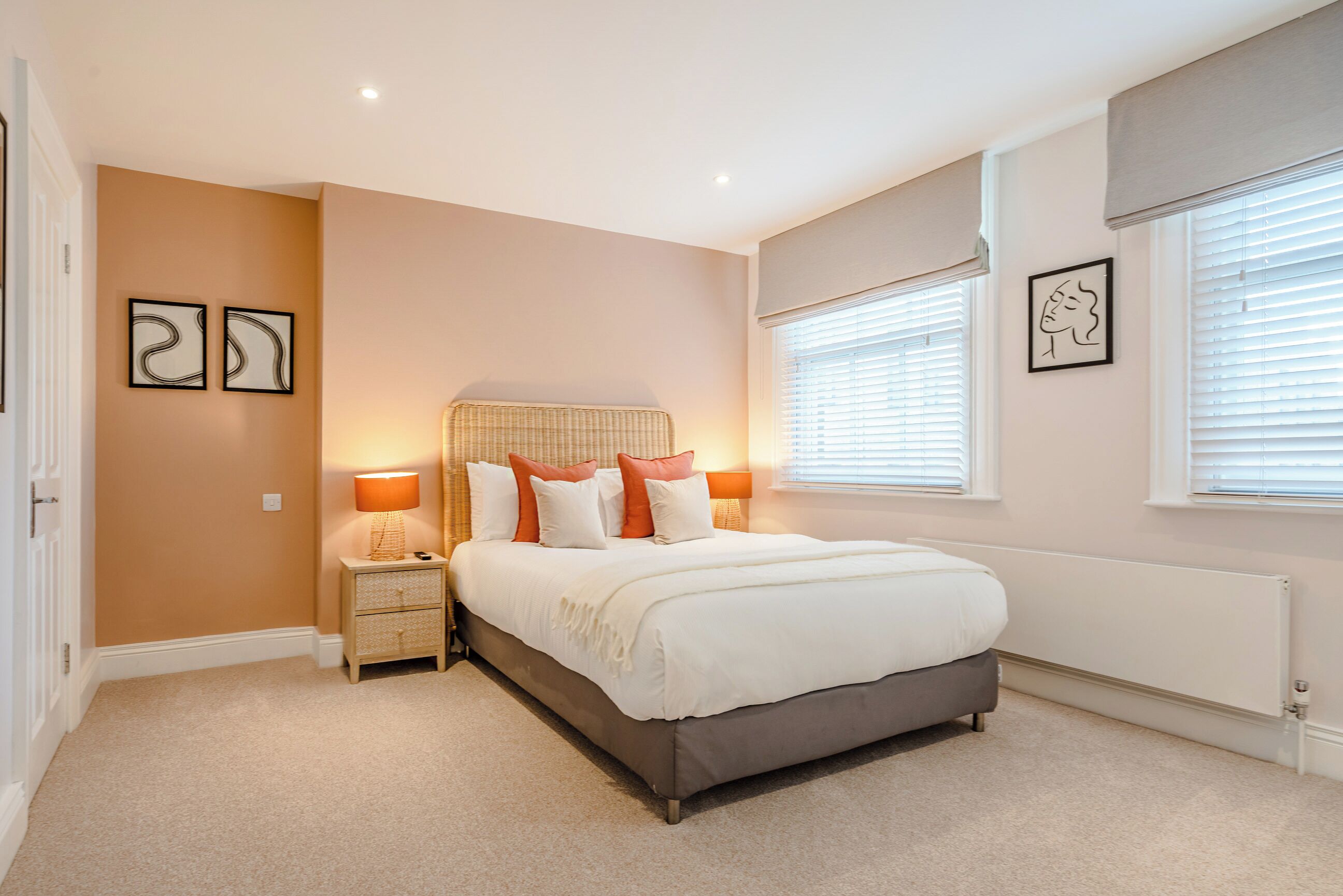A bedroom with a bed, nightstands, and wall art.