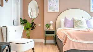 Een slaapkamer met een bed, nachtkastje, stoel en een grote spiegel.