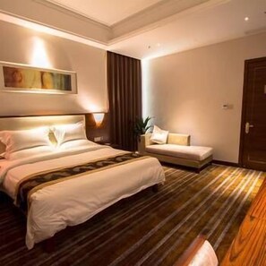 A hotel room with a large bed, a sofa, a painting on the wall, and a wooden floor. - Delin Hotel (Shenzhen)