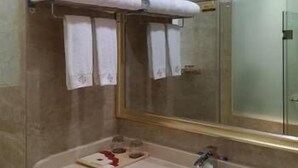 A bathroom with a marble wall, a large mirror, and a towel rack with folded towels. - Delin Hotel (Shenzhen)