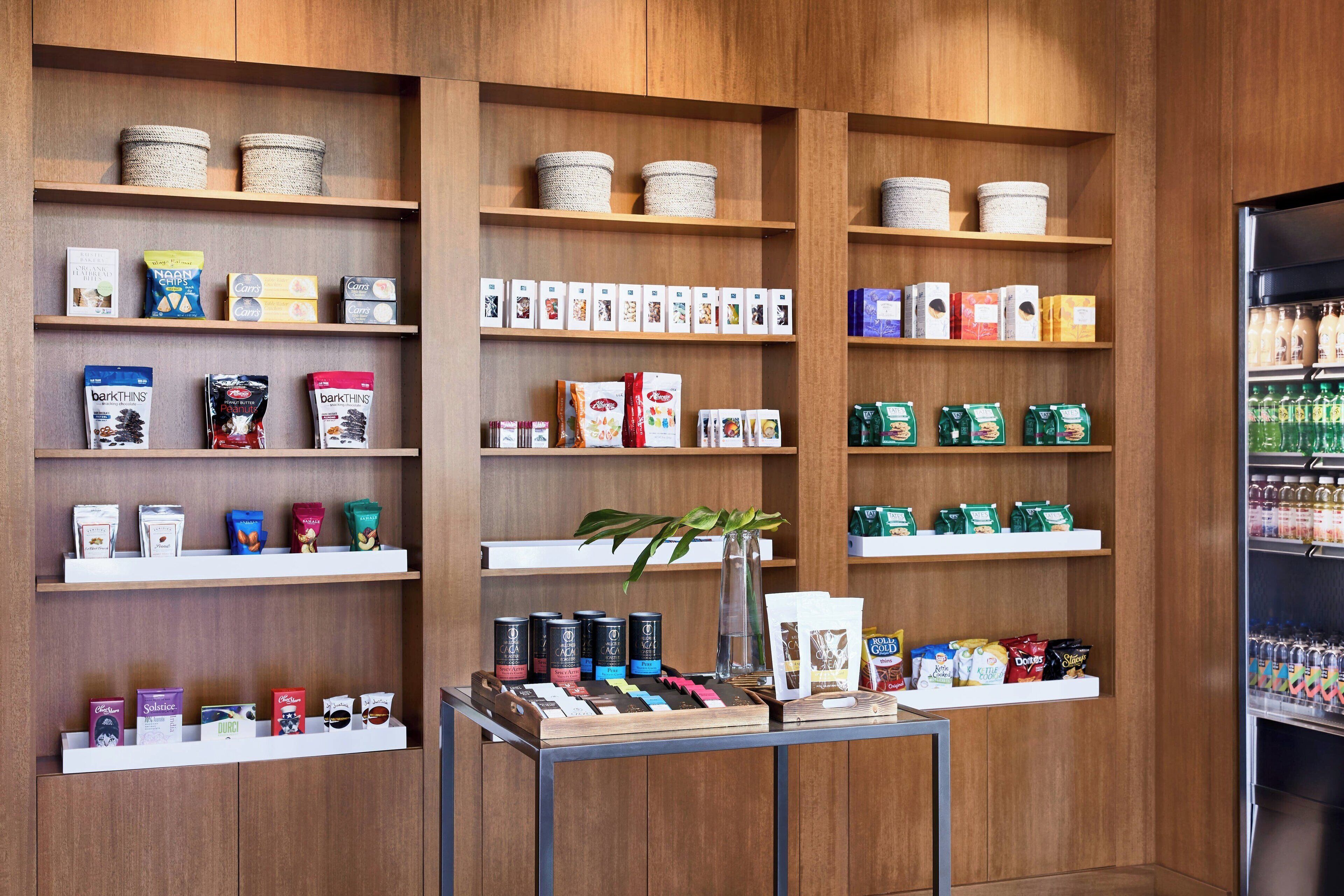 Una tienda con estantes llenos de diversos productos, entre ellos aperitivos, bebidas y alimentos envasados.