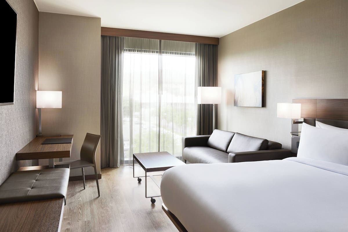 Une chambre d’hôtel moderne, dotée d’un grand lit, d’un canapé, d’un bureau et d’une chaise.