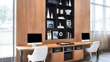 A modern office space with a wooden desk, two white chairs, and a built-in bookshelf with various decorative items.