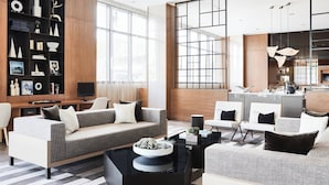 A modern living room with a sofa, coffee table, and a bookshelf filled with decorative items.