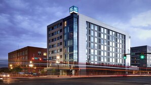 A modern hotel with a prominent AC logo, multiple floors, and a glass facade.