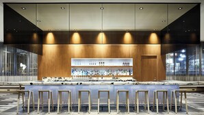 A bar area with a long counter, multiple stools, and a well-lit interior.