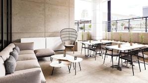 A modern lounge area with a sofa, round tables, and a dining table with chairs.